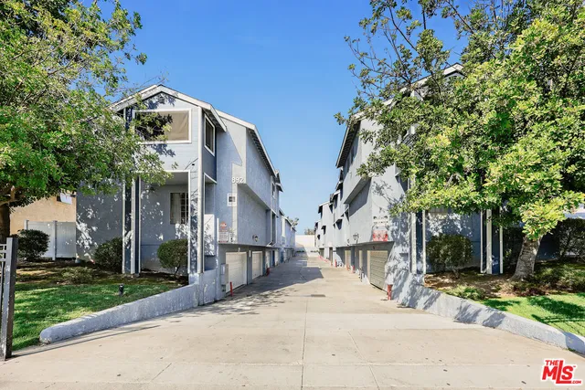 a view of a white house with a large tree