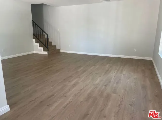 a view of an empty room with wooden floor and entryway