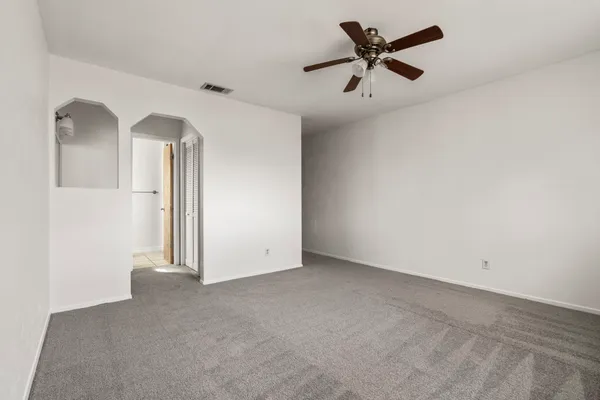 an empty room with closet and a chandelier fan