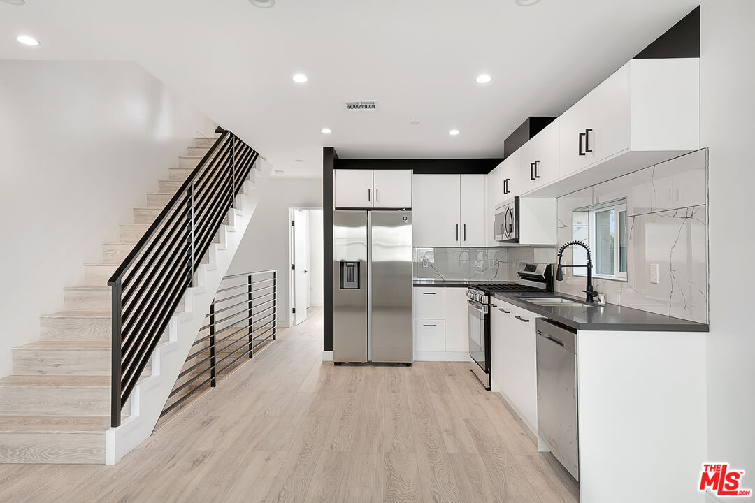 5464 Geer Street Los Angeles, CA 90016 - Photo 3 of 21 a kitchen with stainless steel appliances granite countertop a refrigerator a sink dishwasher and a stove with wooden floor