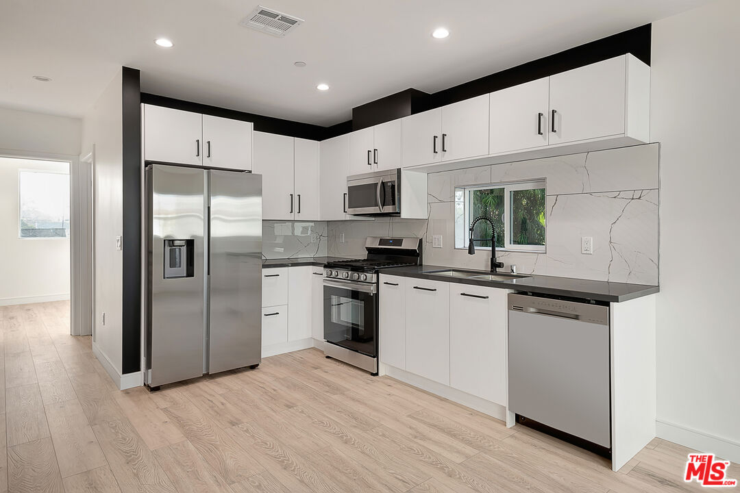 5464 Geer Street Los Angeles, CA 90016 - Photo 4 of 21 a kitchen with stainless steel appliances a refrigerator sink and microwave