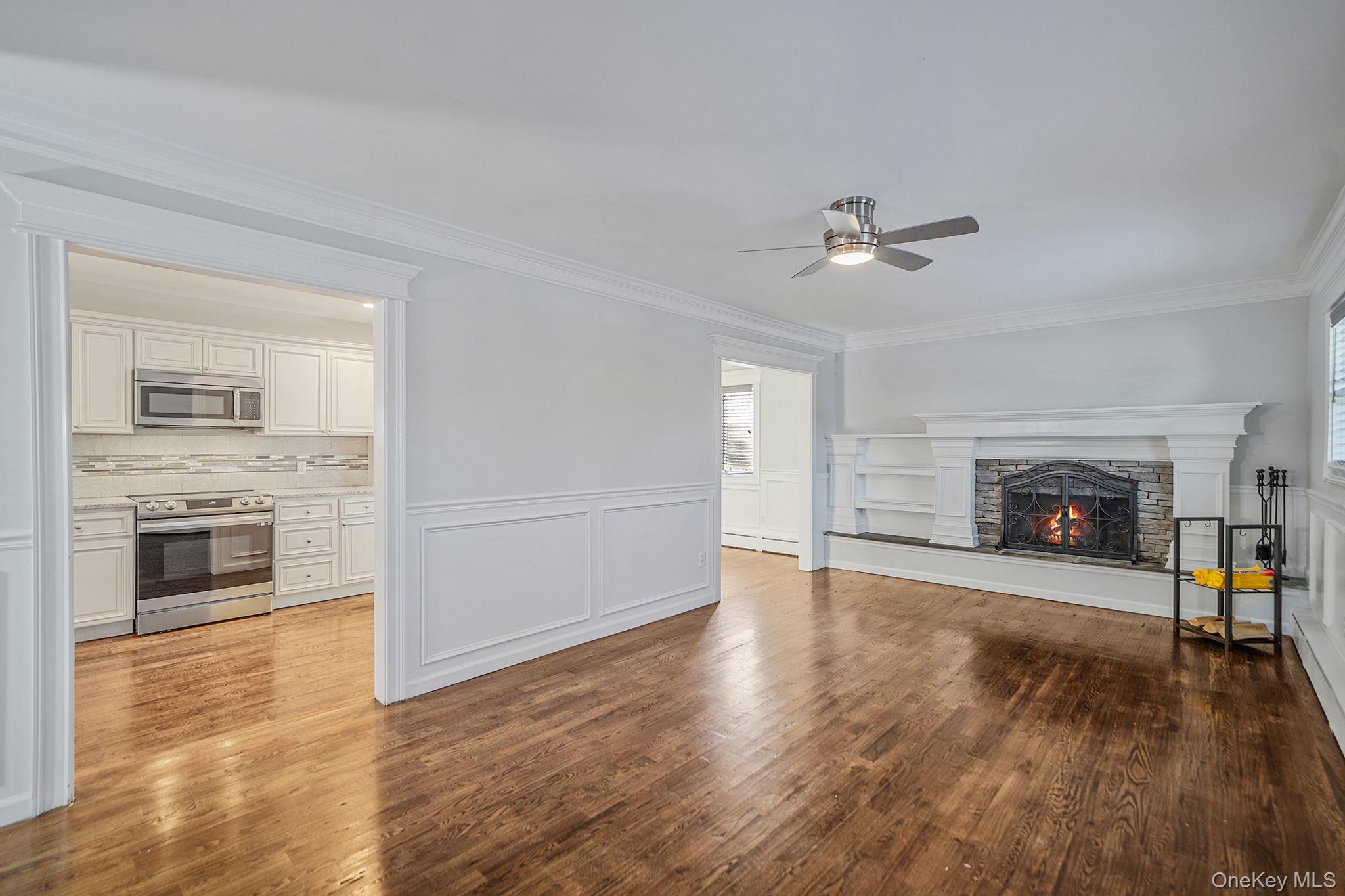 38 Hawthorne Road Rocky Point, NY 11778 - Photo 8 of 30 Living room featuring a decorative wall, a fireplace, crown molding, dark wood-type flooring, and wainscoting
