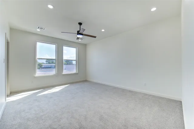 en empty room with windows and ceiling fan