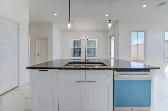 a view of a kitchen with granite countertop a sink and cabinets