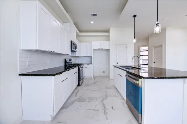 a large kitchen with stainless steel appliances granite countertop a sink a stove and a refrigerator