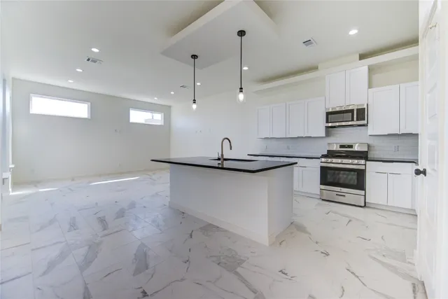 a kitchen with granite countertop a stove a sink and a refrigerator