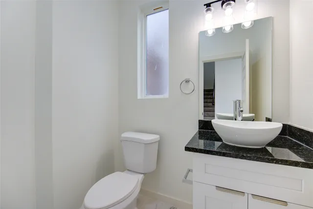 a bathroom with a granite countertop toilet a sink and mirror