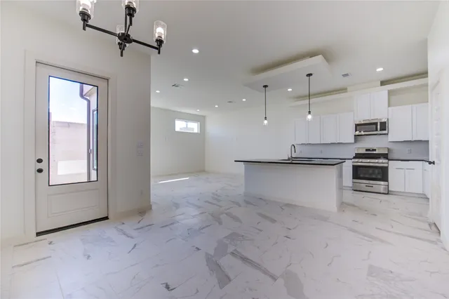 a view of kitchen with stainless steel appliances kitchen island granite countertop a stove top oven a sink and a refrigerator
