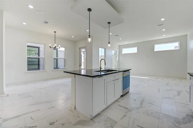 a large kitchen with stainless steel appliances kitchen island granite countertop a sink a counter space and a window