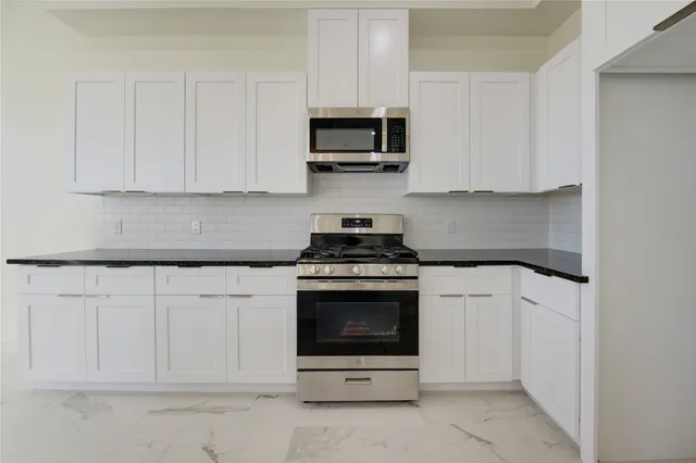 a kitchen with white cabinets and stainless steel appliances
