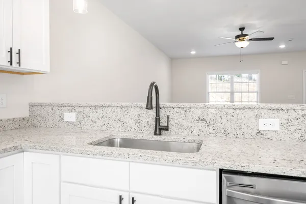 a kitchen with granite countertop a sink and a white wooden cabinets