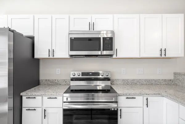 a kitchen with stainless steel appliances granite countertop white cabinets and a stove a oven with white countertops