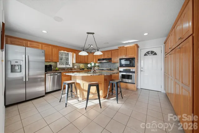 a kitchen with stainless steel appliances kitchen island granite countertop a refrigerator and a sink
