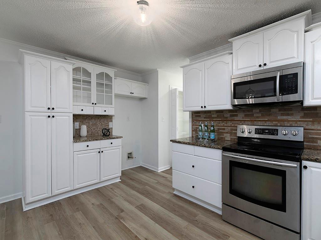 62 Smoak Field Road Griffin, GA 30223 - Photo 21 of 50 a kitchen with stainless steel appliances white cabinets a stove a sink and a microwave