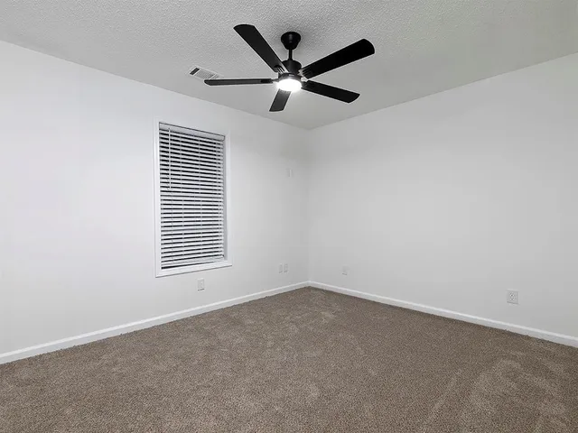 an empty room with a window and a ceiling fan