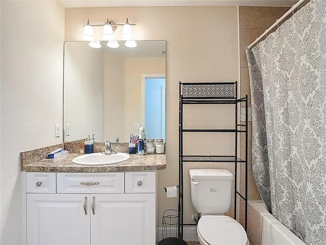 a bathroom with a granite countertop sink a mirror and shower