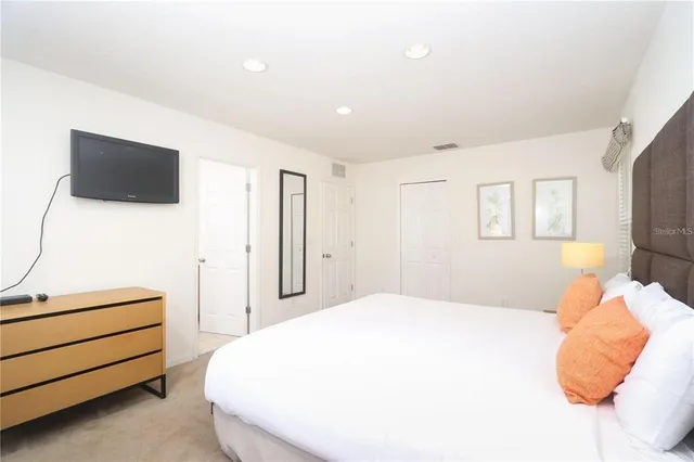 a spacious bedroom with a bed and a flat screen tv