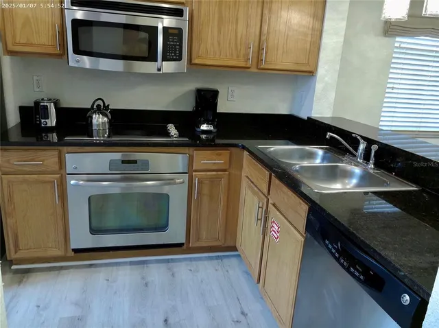 a kitchen with granite countertop a stove top oven microwave and sink
