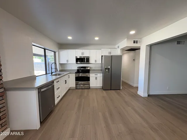 a large kitchen with stainless steel appliances granite countertop a stove a sink and a refrigerator