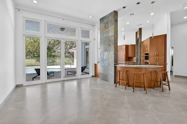 a view of an empty room with a floor to ceiling window and kitchen