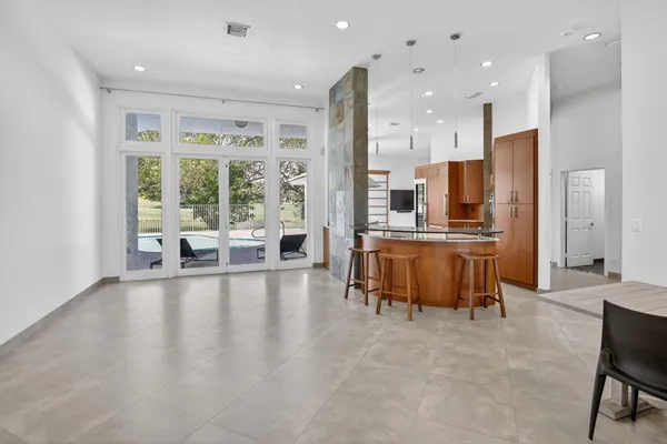 a large white kitchen with kitchen island a large window a couch and furniture