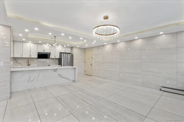 a view of kitchen with stainless steel appliances kitchen island granite countertop a sink and white cabinets