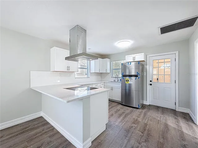 a kitchen with a refrigerator a stove and wooden floor