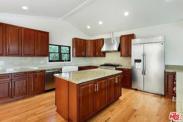 a kitchen with stainless steel appliances granite countertop wooden cabinets a stove a sink and a refrigerator