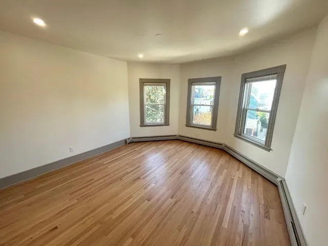 a view of an empty room with wooden floor and window