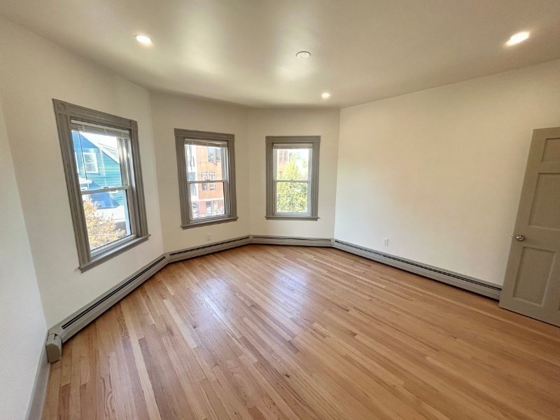 116 Prospect Street, Unit 1 Somerville, MA 02143 - Photo 14 of 21 an empty room with wooden floor and windows