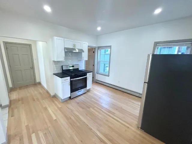 a kitchen with granite countertop a refrigerator and a stove top oven