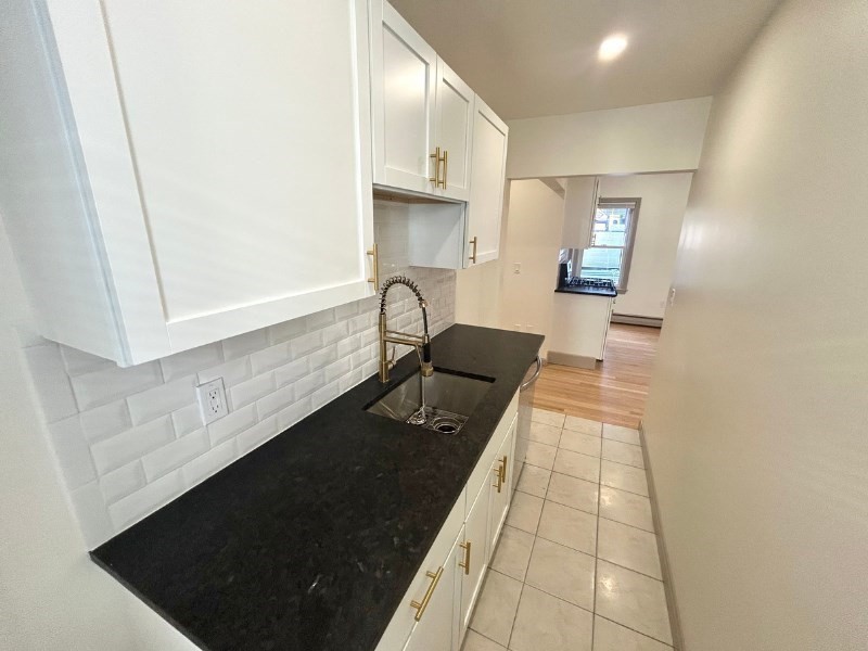 116 Prospect Street, Unit 1 Somerville, MA 02143 - Photo 7 of 21 a hallway with white cabinets and black appliances