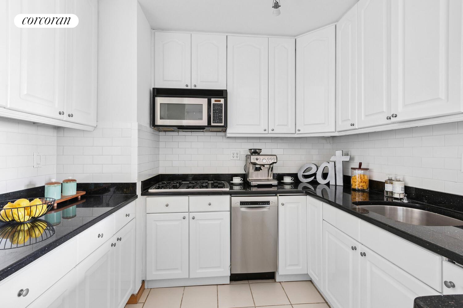 117 East 57th Street, Unit 32G Manhattan, NY 10022 - Photo 4 of 13 a kitchen with granite countertop white cabinets and stainless steel appliances