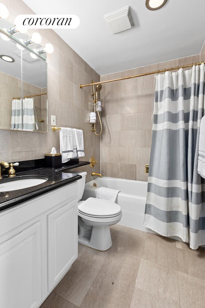 117 East 57th Street, Unit 32G Manhattan, NY 10022 - Photo 6 of 13 a bathroom with a double vanity sink a toilet a shower and a mirror