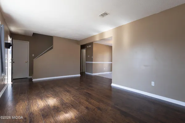 a view of an empty room with wooden floor and a window