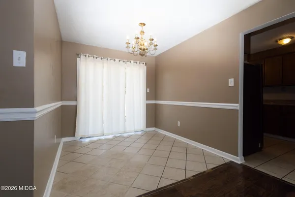 a view of an empty room with window and chandelier