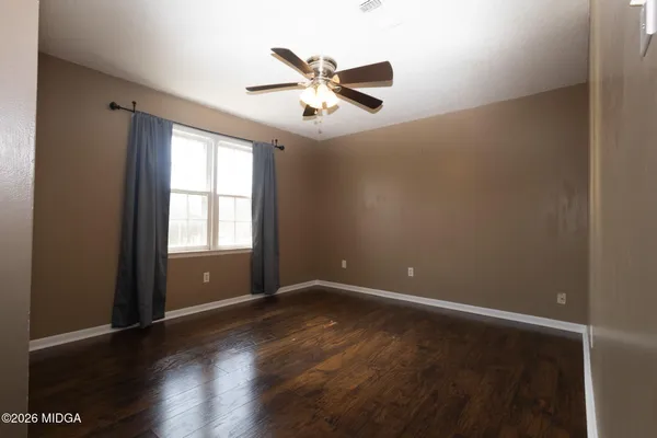 an empty room with wooden floor fan and windows