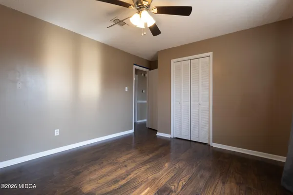 an empty room with wooden floor chandelier fan and closet area