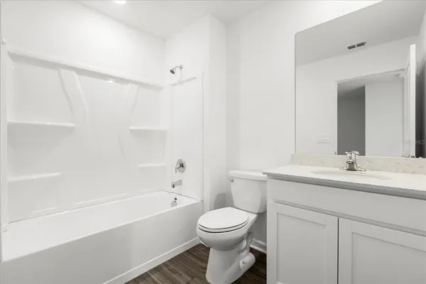 a bathroom with a toilet a sink a mirror a bathtub and vanity