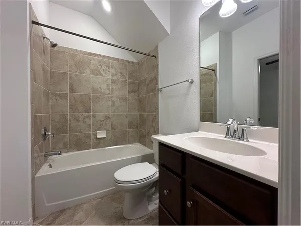 an empty room with chandelier fan and windows