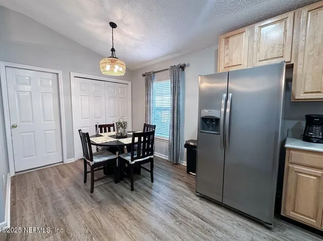 a view of a dining room and livingroom with furniture wooden floor a rug a painting and a chandelier