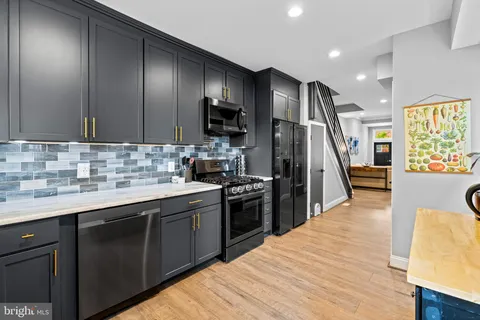 a kitchen with stainless steel appliances sink stove microwave and wooden floor