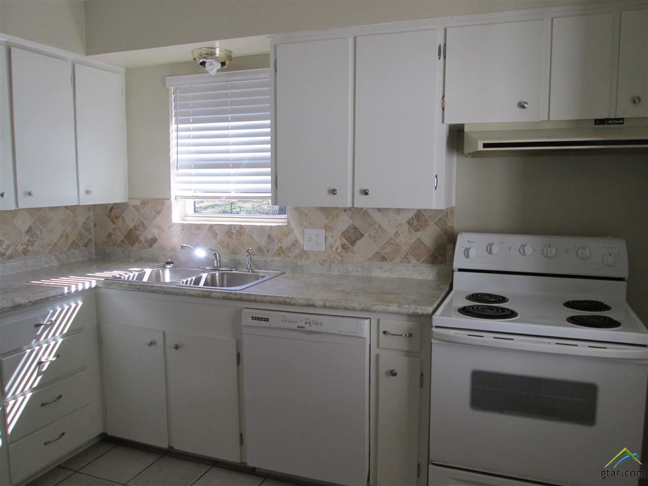 2409 Mimosa Drive Tyler, TX 75701 - Photo 7 of 35 a kitchen with granite countertop white cabinets and white appliances
