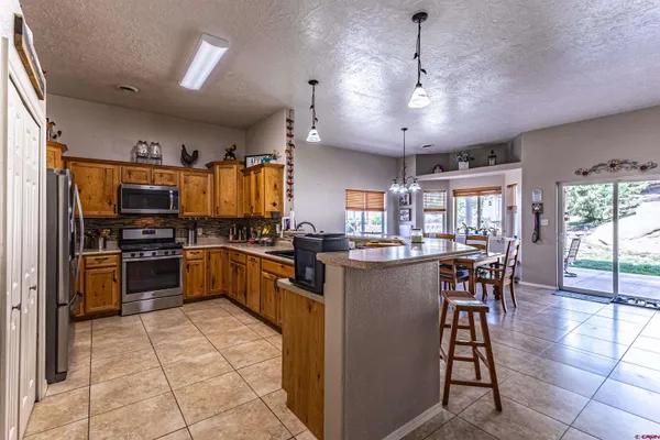 a kitchen with stainless steel appliances kitchen island granite countertop a stove refrigerator and cabinets