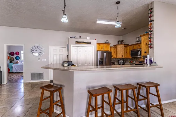 a kitchen with stainless steel appliances granite countertop a dining table chairs refrigerator and sink
