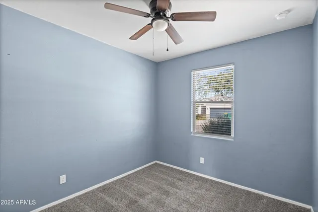 an empty room with windows and fan