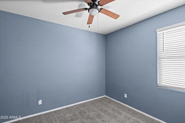 an empty room with chandelier fan and windows