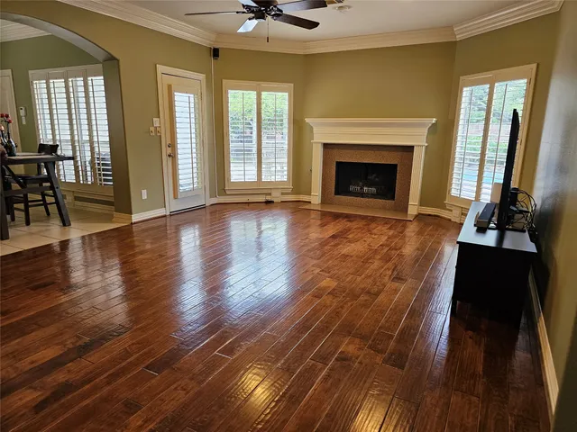 a view of an empty room with wooden floor and a fireplace