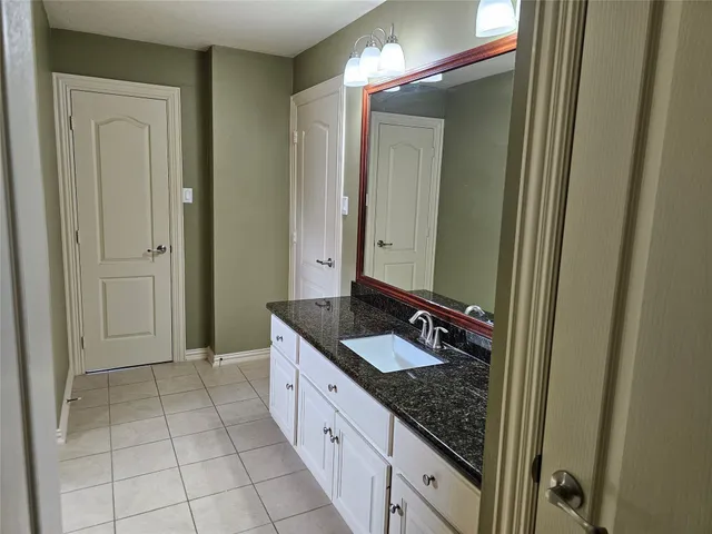 a spacious bathroom with a granite countertop sink and a mirror