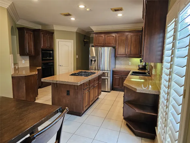 a kitchen with stainless steel appliances kitchen island granite countertop a stove and a refrigerator